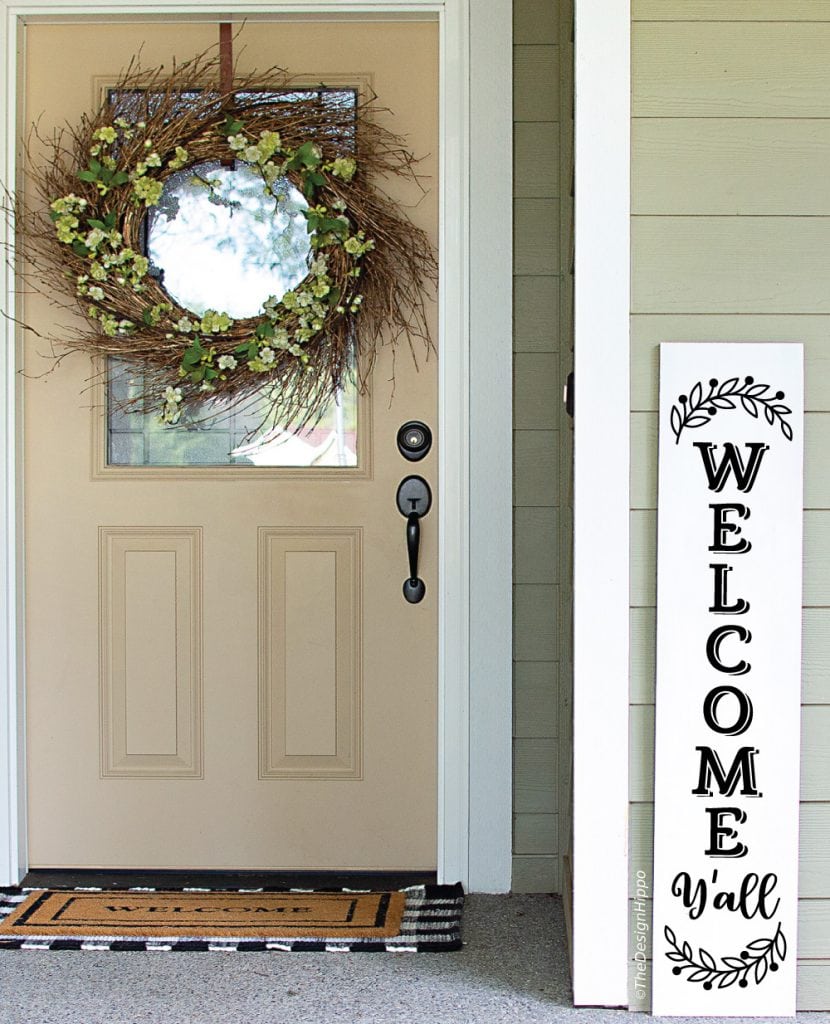 wood sign with floral elements displayed on a white vertical porch sign
